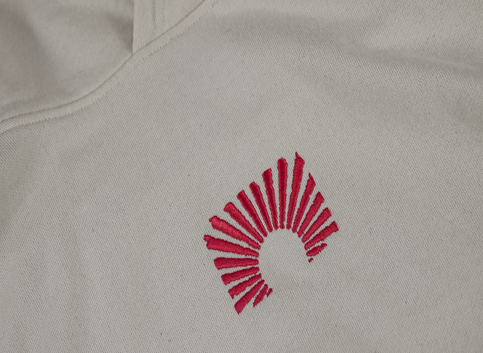 Nahaufnahme eines cremefarbenen Hoodies mit roter Stickerei
